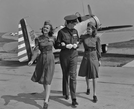 Photographie en noir et blanc d’un pilote avec 2 hôtesses de l’air.