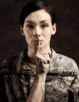 Photographie d'une militaire avec un doigt d'homme sur la bouche (silence)