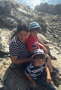 Camélia assise en bord de mer avec ses 2 enfants.