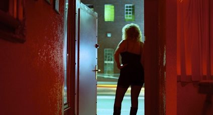 Photo d'une femme de dos adossée à une porte.