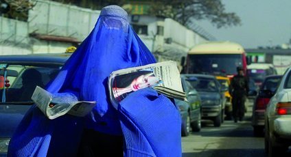 Photographie d'une femme afghane transportant des journaux