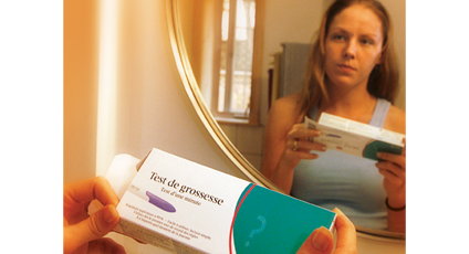 Photographie d'une femme devant un miroir avec un test de grossesse