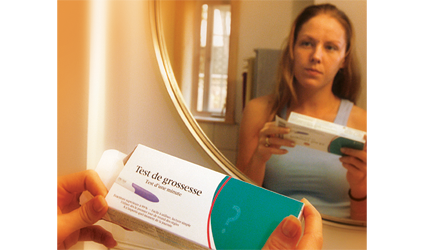 Photographie d'une femme devant un miroir avec un test de grossesse