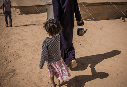 Une femme réfugiée tenant une enfant pas la main.