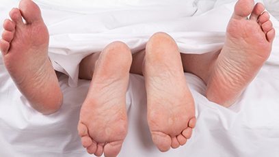 Photographie d'un couple au lit, sous les couvertures