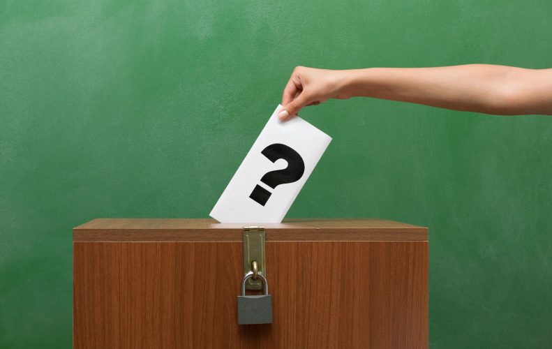 Photographie d’une personne remettant son buletin de vote dans l’urne