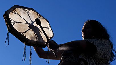 Photographie d’un autochtone frappant sur un tambour