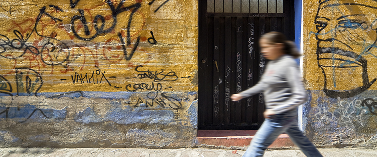 Femme marchant devant un mur avec graffiti.