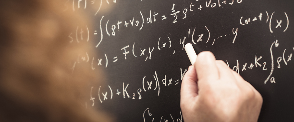 Femme inscrivant formules mathématiques sur un tableau.