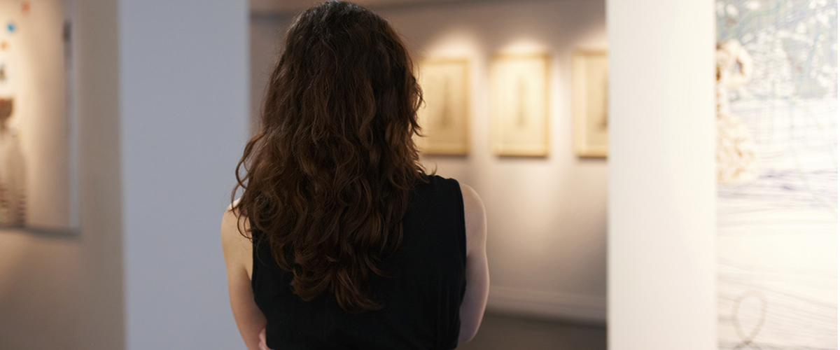 Photographie une jeune femme vue de dos, regardant une galerie.