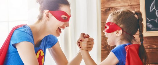 Mère et fille déguisée en super héros rigolant ensemble.