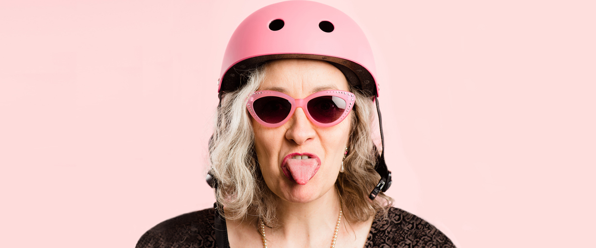 Femme avec un casque et des lunettes rose et faisant une grimace.