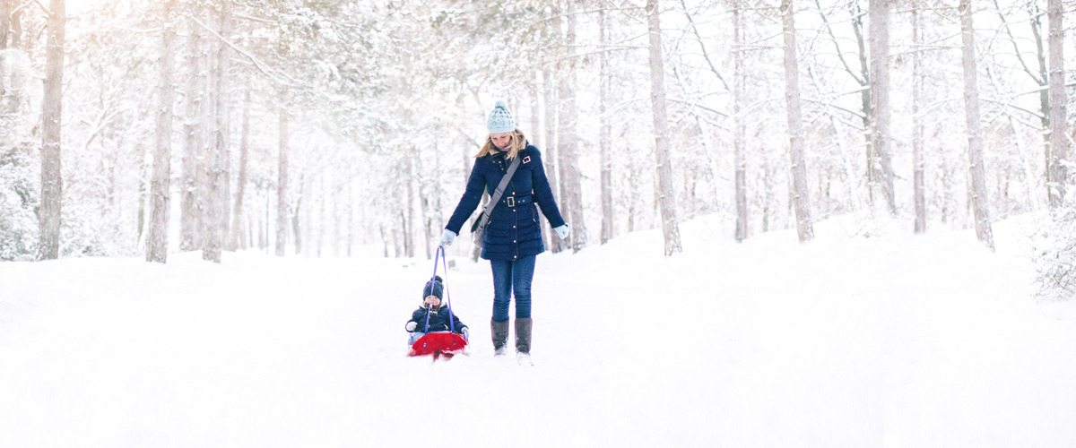 Photographie d'une femme se promenant dans le bois en hiver avec son fils.